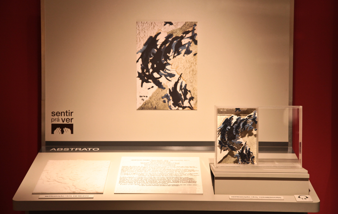 Bancada acessível da exposição com o tema Natureza Morta, contendo reprodução fotográfica, maquete e relevo tátil e texto em dupla leitura da obra de Leopoldo Raimo, sem título, 1958.