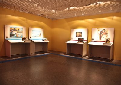 foto na horizontal de quatro bancadas acessíveis da exposição, tema marinha e cena.