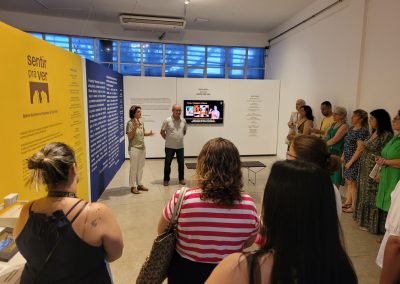 Foto de Amanda e Alfonso na entrada da exposição com grupo de trinta professores.