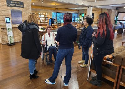 Treinamento com educadores, Amanda Tojal em simulação sentada em cadeira de rodas, ao redor dela educadores escutam explicação.