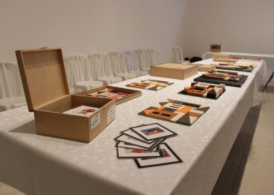 Foto de uma mesa com diversos jogos de quebra cabeça com temas da exposição.