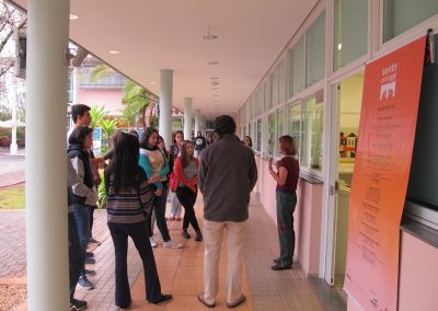 Grupo de estudantes ouvem instruções de Amanda Tojal sobre exposição.