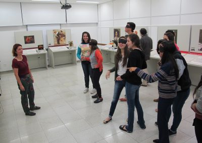 Amanda com grupo de estudantes na exposição, alguns estão com olhos vendados para experiência tátil.